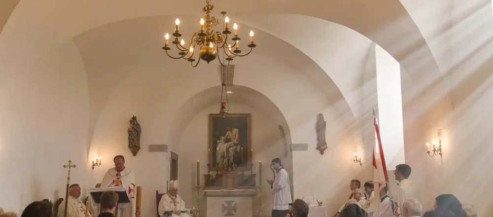 Liturgie v zámecké kapli při svíčkách pod lustrem
